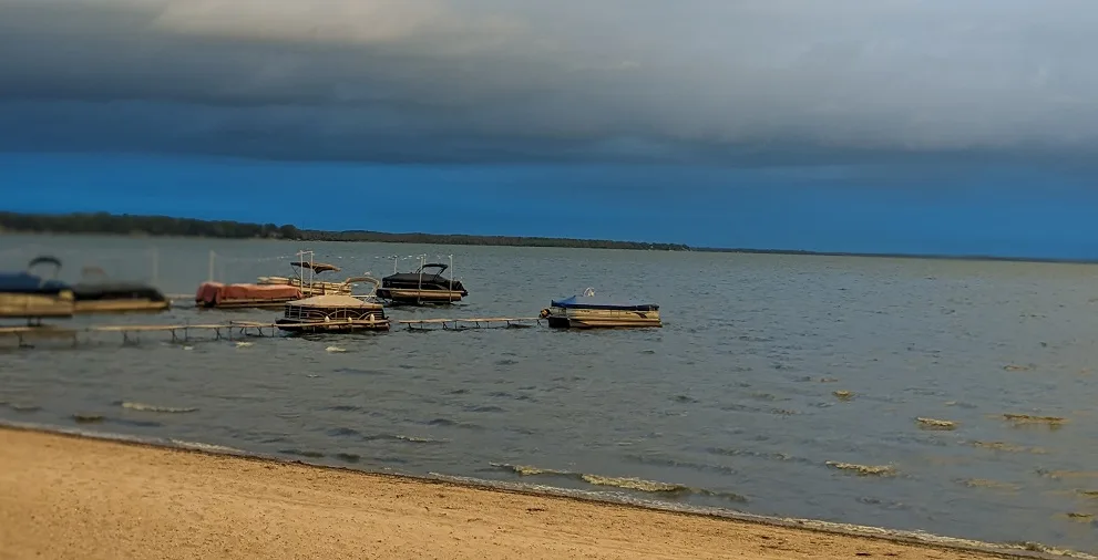 Boats moored beside the sandy beach on Lake Koshkonong